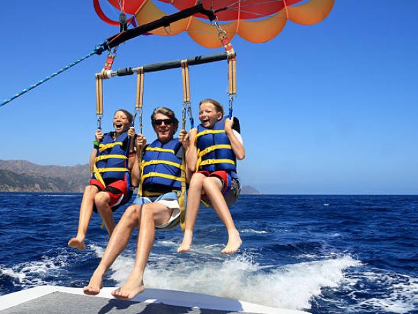 Father and Twin Daughters Parasailing Against a Blue Summer Sky.